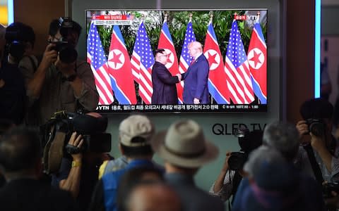 People watch a television screen showing live footage of the summit between US President Donald Trump and North Korean leader Kim Jong-un in Singapore, at a railway station in Seoul - Credit: Jung Yeon-je/AFP