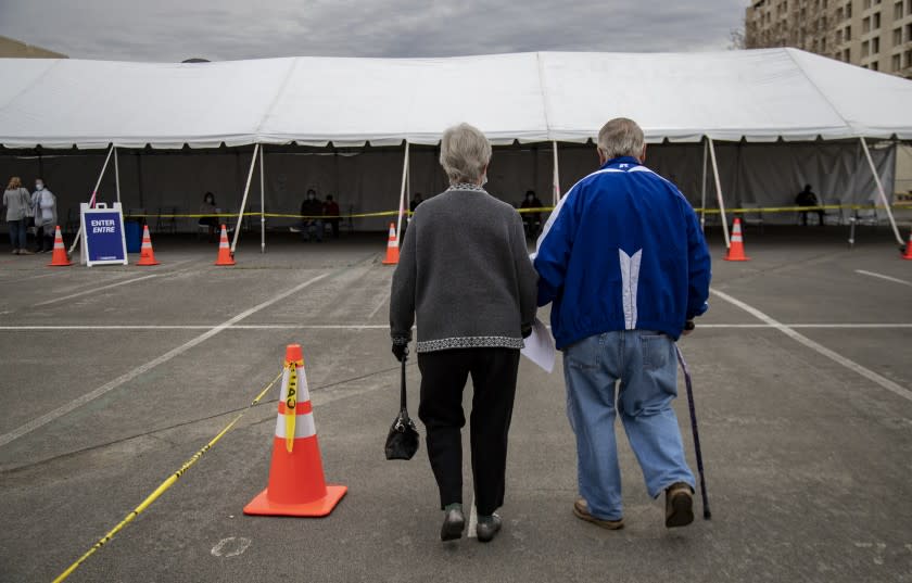 RIVERSIDE, CA - FEBRUARY 1, 2021: Robert Nelson,81, of Riverside holds his wife Norma's hand as they walk to the observation lounge area after he received the Moderna vaccination in the parking lot of the Riverside Convention Center on February 1, 2021 in Riverside, California. Norma,83, received her vaccination a couple days earlier. Currently, this site is capable of giving 500 vaccinations a day in one of the regions hardest hit by the pandemic. Only residents 65 and older and educators are eligible for the vaccination here.(Gina Ferazzi / Los Angeles Times)