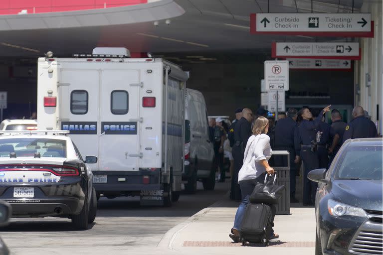 Una viajera se abre paso entre el personal de emergencia que se encuentra fuera de la zona de venta de billetes y facturación en Dallas Love Field en Dallas, tras un tiroteo, el lunes 25 de julio de 2022.