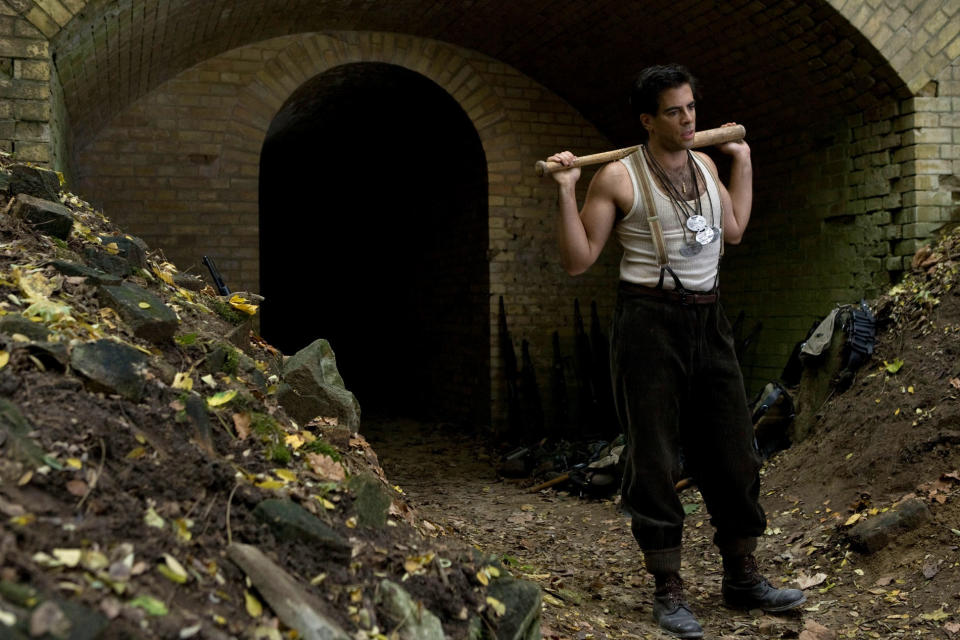 A man stands holding a baseball bat