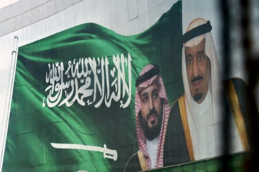 Saudi King Salman and his son Crown Prince Mohammed appear next to a Saudi flag on a billboard in Riyadh