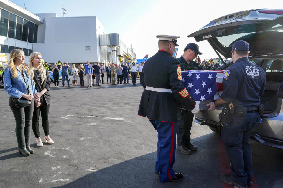 Teresa Irwin, left, sister of Marine Capt. Grady Kurpasi, watches as Marine First Sgt. Timothy La Sage, center, and Port Authority police officer place his remains into an waiting car at New York's John F. Kennedy International Airport, Friday, May 19, 2023, in New York. The remains of a U.S. Marine veteran who had been missing in Ukraine for more than a year will be returned to his family in eastern North Carolina later Friday, according to the group bringing the remains back to the U.S. (AP Photo/Mary Altaffer)