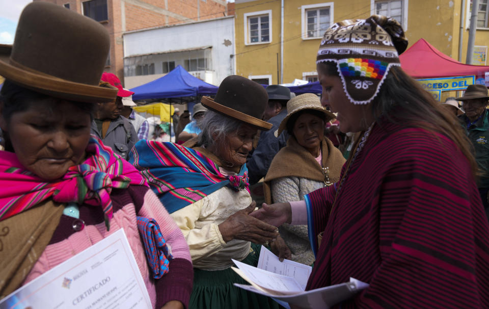 An Aymara woman, center, shake hands to her teacher after receiving her certificate during an adult literacy graduation ceremony in Pucarani, Bolivia, Sunday, Dec. 4, 2022. (AP Photo/Juan Karita)