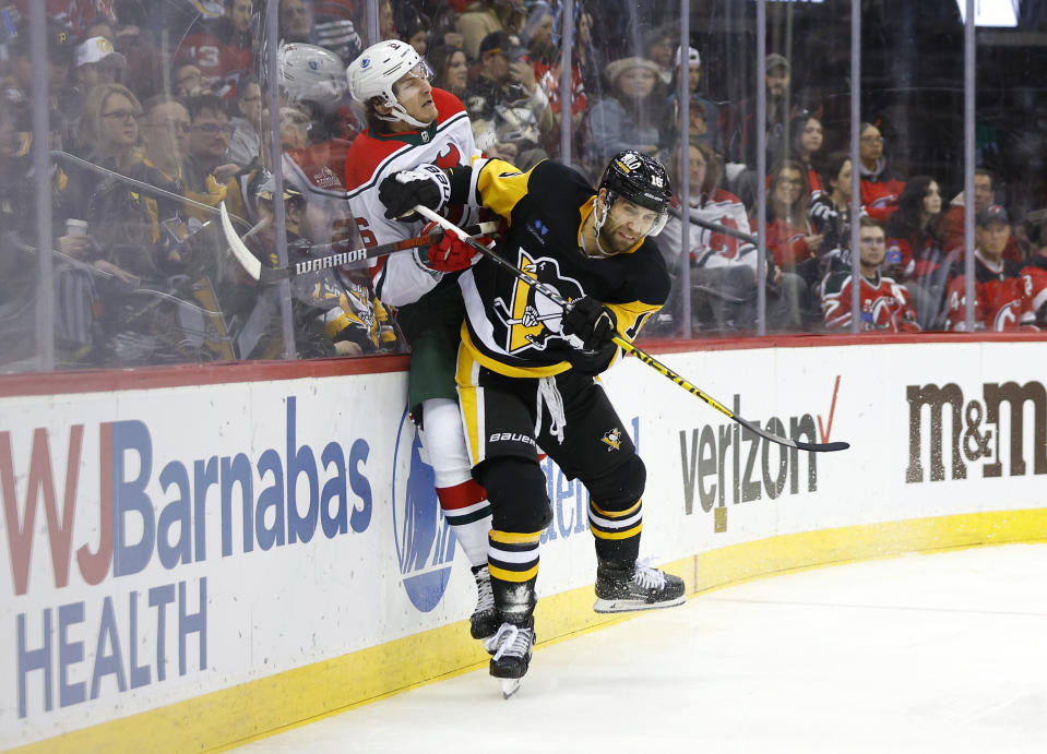 Pittsburgh Penguins left wing Jason Zucker (16) checks New Jersey Devils defenseman John Marino (6) during the first period of an NHL hockey game Tuesday, April 4, 2023, in Newark, N.J. (AP Photo/Noah K. Murray)