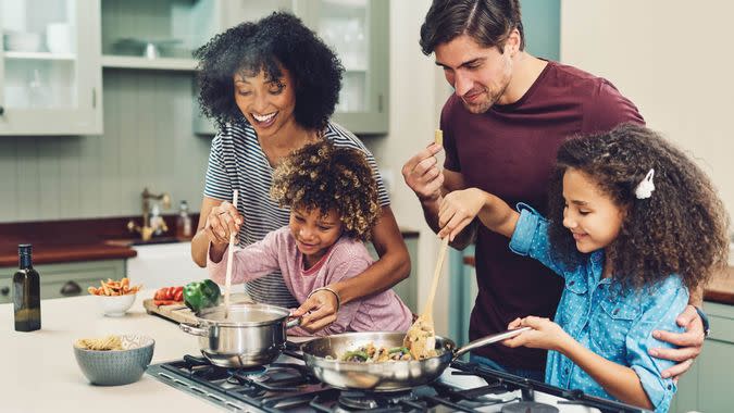 Shot of a family of four cooking together in their kitchen at home.