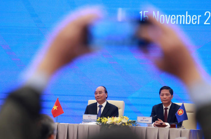 Vietnamese Prime Minister Nguyen Xuan Phuc, left, and Minister of Trade Tran Tuan Anh, right, attend a virtual signing ceremony of the Regional Comprehensive Economic Partnership, or RCEP, trade agreement in Hanoi, Vietnam on Sunday, Nov. 15, 2020. China and 14 other countries agreed Sunday to set up the world’s largest trading bloc, encompassing nearly a third of all economic activity, in a deal many in Asia are hoping will help hasten a recovery from the shocks of the pandemic.(AP Photo/Hau Dinh)