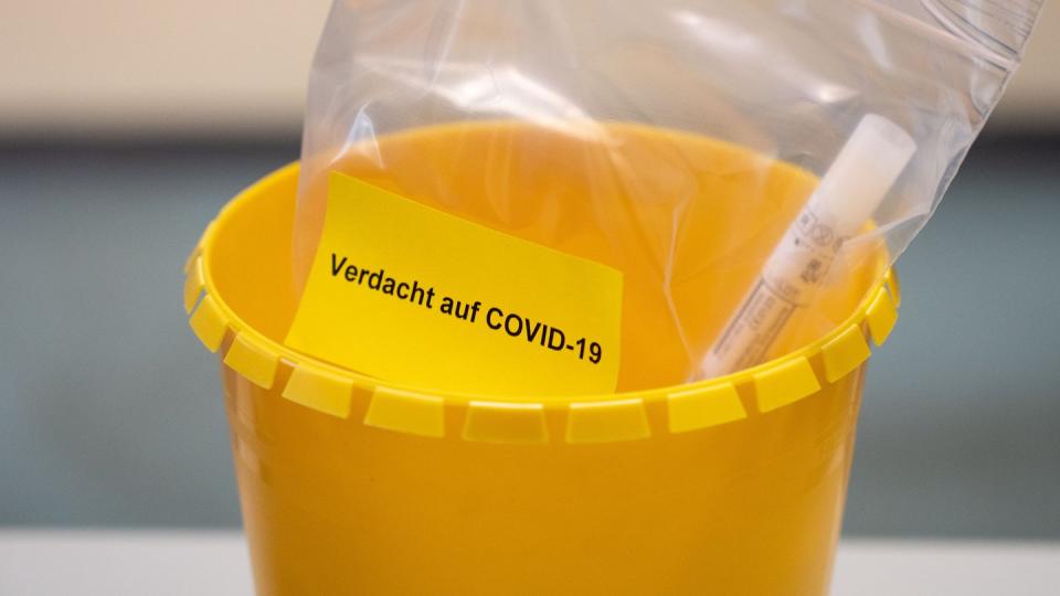 Ein Teströhrchen liegt in einer Tüte mit der Aufschrift «Verdacht auf COVID-19».