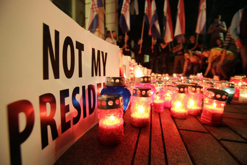 People lace candles by a poster reading "not my president" during protest in Mostar, Bosnia, Thursday, Oct. 11, 2018. Several thousand Bosnian Croat nationalists have protested the election victory of a moderate politician last weekend in the race for the Croat seat in Bosnia's three-person presidency. The crowd Thursday marched through the ethnically divided southern town of Mostar holding banners reading "Not my president" and "RIP democracy" in protest at the election of Zeljko Komsic." (AP Photo/Amel Emric)