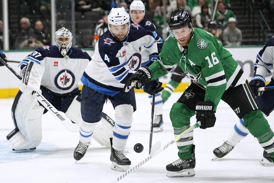 Winnipeg Jets defenseman Neal Pionk (4) and Dallas Stars center Joe Pavelski (16) chase the puck during the first period of an NHL hockey game in Dallas, Thursday, Feb. 29, 2024. (AP Photo/Tony Gutierrez)