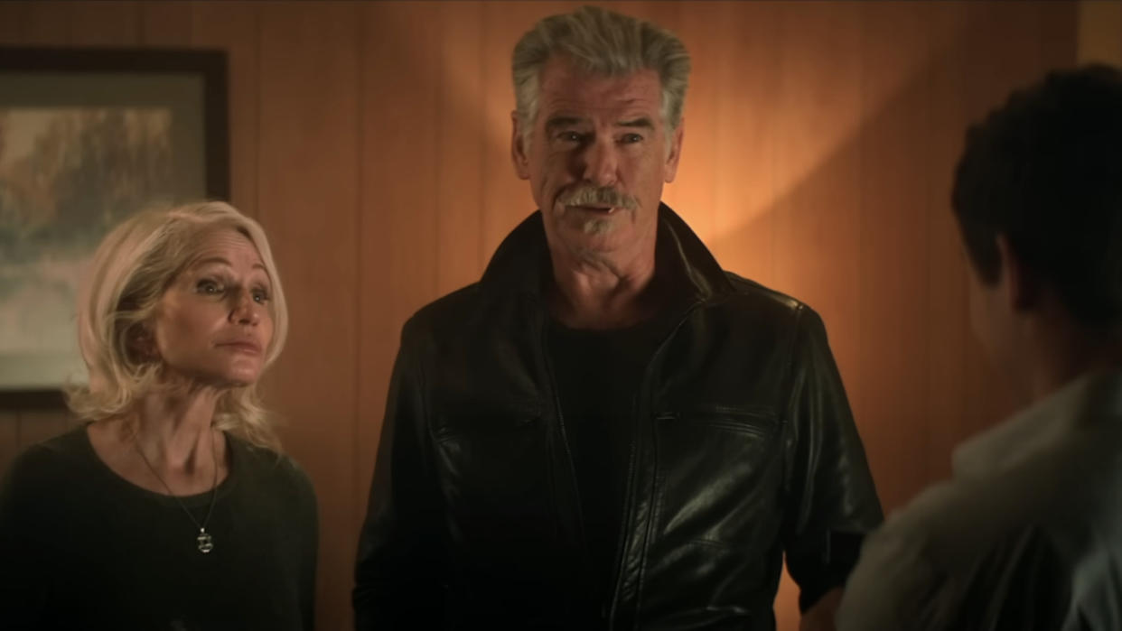  Ellen Barkin and Pierce Brosnan looking amused while standing in a hotel room in The Out-Laws. 