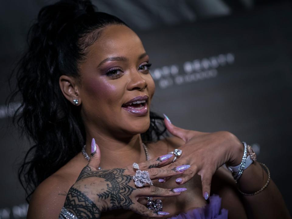 Rihanna poses with hands under her face at Fenty Beauty launch in London