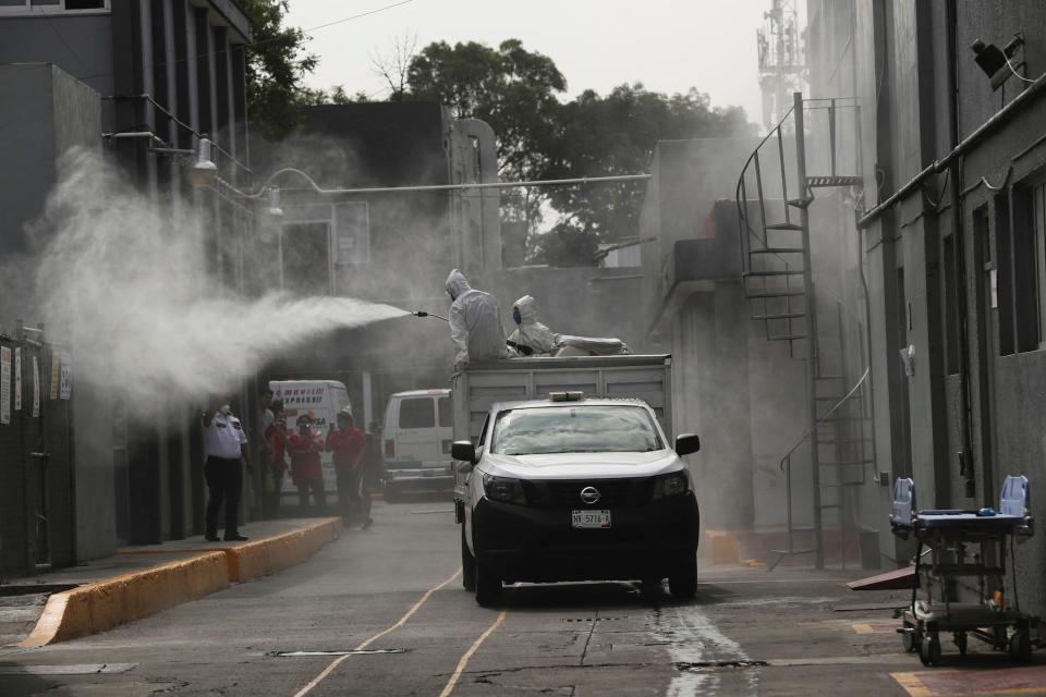 City workers wearing protective gear disinfect an area outside of a public hospital where staff members are protesting their lack of protective gear, in Mexico City in April.