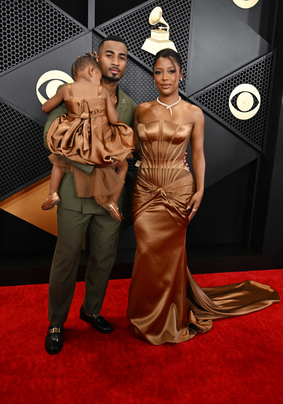 John Gaines, Victoria Monét and daughter Hazel Monét Gaines at the 66th Annual GRAMMY Awards held at Crypto.com Arena on February 4, 2024 in Los Angeles, California, bronze atelier versace corset dress