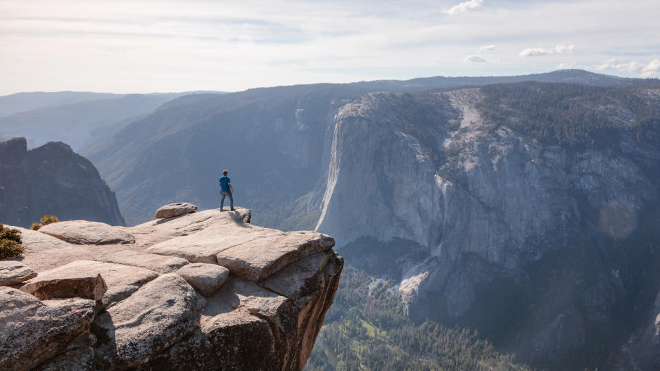 A man standing on a cliff edge overlooking Yosemite Valley