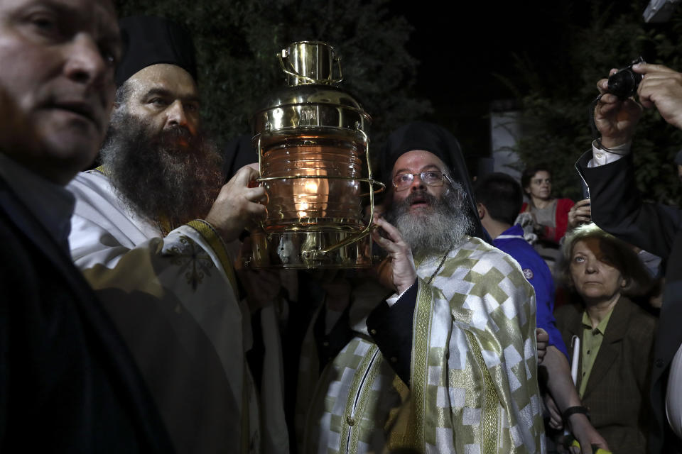 Greek Orthodox priests carry a lantern with the "Holy Flame" brought from Jerusalem, at a church in Athens, on Saturday, April 27, 2019. A lantern carrying a flame lit in Jerusalem's Holy Sepulcher Church was welcomed in Greece with honors reserved for visiting heads of state. But a senior cleric boycotted the ceremony, miffed that the "Holy Flame" did not land within his see.(AP Photo/Yorgos Karahalis)