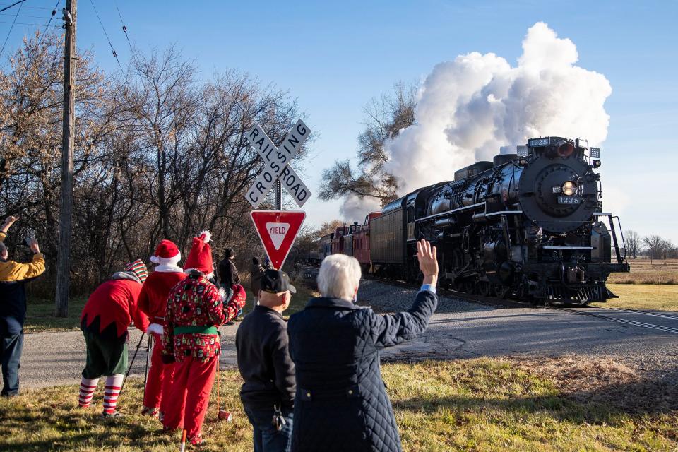 People wave at the North Pole Express pulled by the steam engine Pere Marquette 1225 approach Ashley station from Owosso on Friday, Nov. 24, 2023.