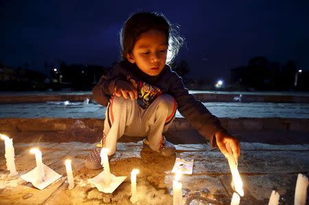 A boy lights a candle during a candle light vigil to remember the victims of last week's earthquake in Kathmandu, Nepal 2 May 2015. REUTERS/Navesh Chitrakar