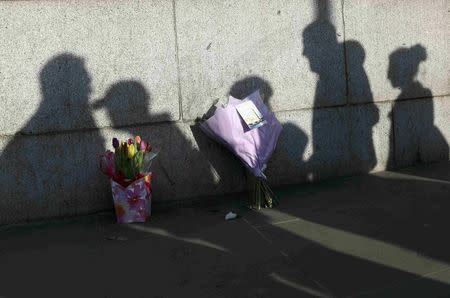 Silhouettes of passers by fall across tributes, following a recent attack in Westminster, London, Britain March 24, 2017. REUTERS/Neil Hall