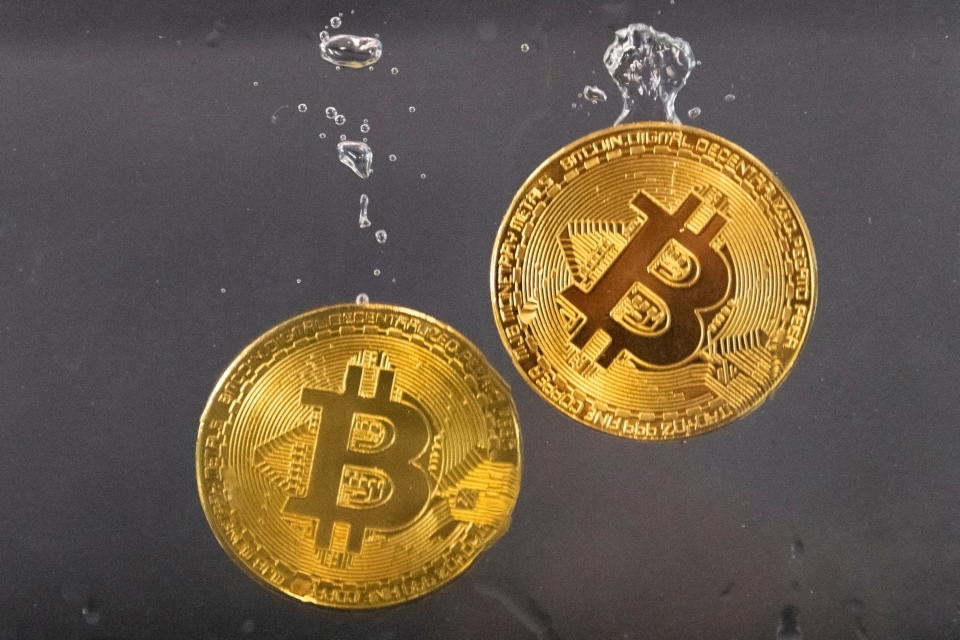 Souvenir tokens representing cryptocurrency Bitcoin plunge into water in this illustration taken May 17, 2022. REUTERS/Dado Ruvic/Illustration