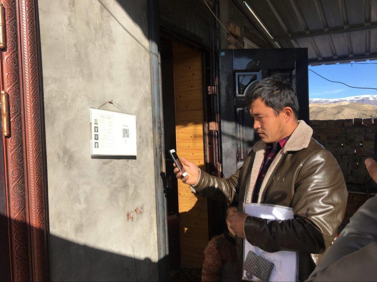 A government official scans the code outside a home in Xinjiang province: Xinjiang state radio