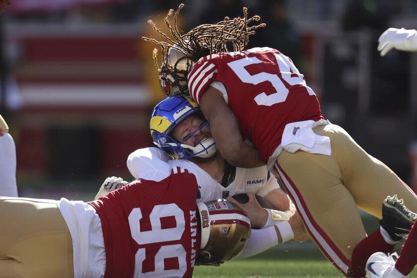 Rams quarterback Carson Wentz is tackled by 49ers Javon Kinlaw (99) and linebacker Fred Warner.