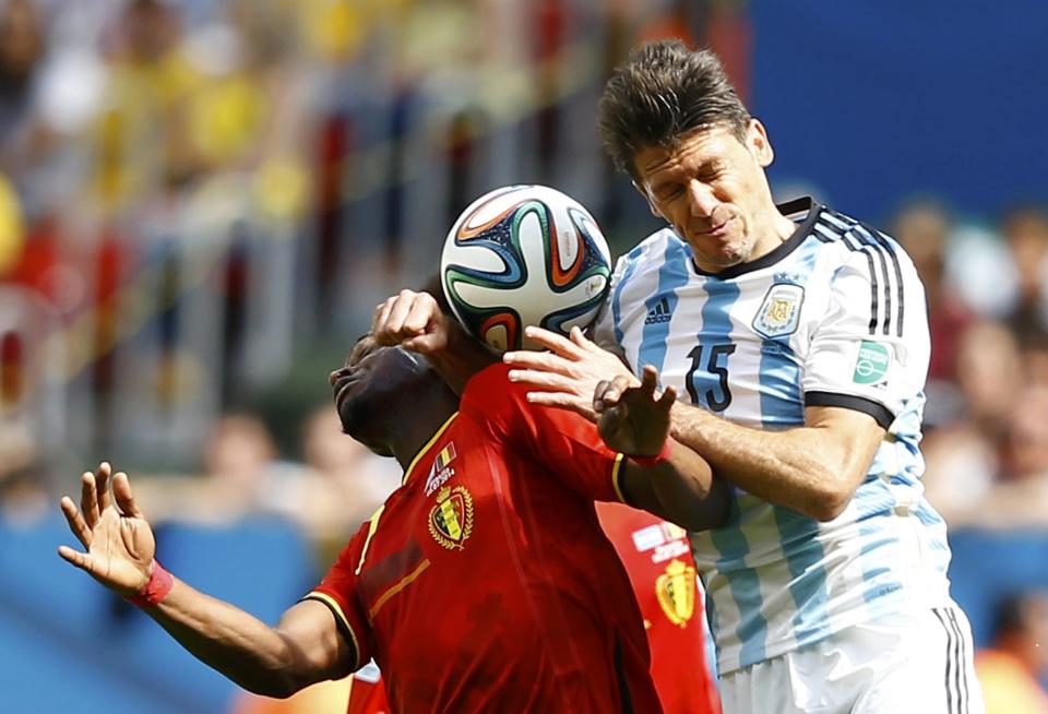 Belgium's Divock Origi jumps for the ball with Argentina's Martin Demichelis during their 2014 World Cup quarter-finals at the Brasilia national stadium in Brasilia July 5, 2014. REUTERS/Dominic Ebenbichler