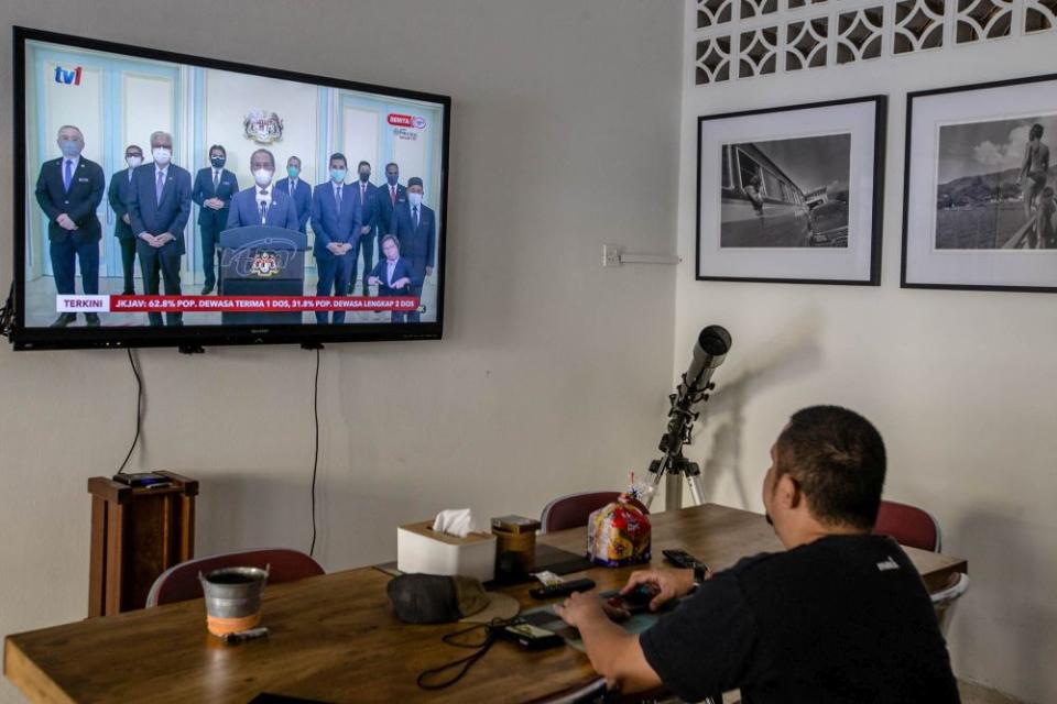 A man watches a live telecast of Prime Minister Tan Sri Muhyiddin Yassin’s speech in Kuala Lumpur August 4, 2021. Parti Pejuang Tanah Air (Pejuang) today denied signing a statutory declaration (SD) in support of Muhyiddin. — Picture by Firdaus Latif