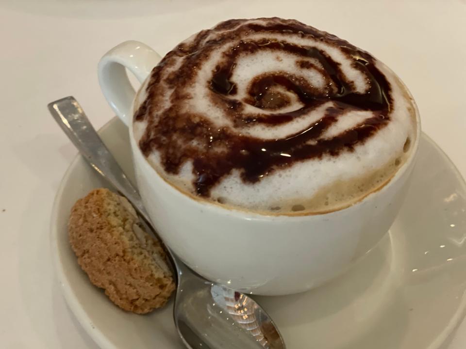 decaf coffee on a saucer with a small biscuit cookie