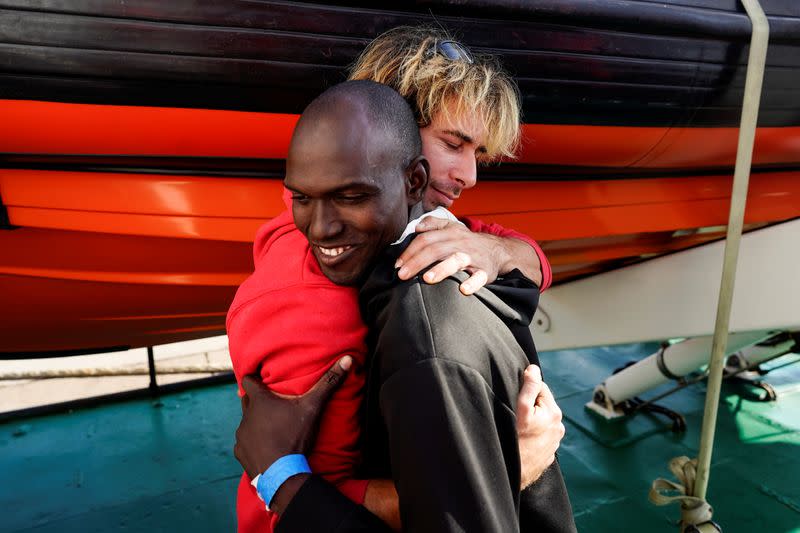 FILE PHOTO: A crew member embraces a migrant on board of NGO Proactiva Open Arms rescue boat, at the Port of Taranto