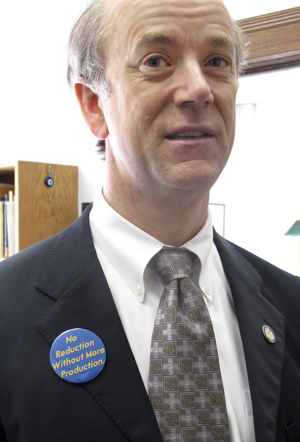 Sen. Hollis French poses with a pin bearing his philosophy on oil taxes on Wednesday, April 18, 2012, in Juneau, Alaska. The pin reads: "No Reduction Without More Production." (AP Photo/Becky Bohrer)