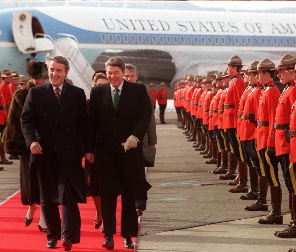 Prime Minister Brian Mulroney and President Ronald Reagan walk past a line of Royal Canadian Mounted Police  March 17, 1985 at the Quebec City airport.Following are Mrs. Mila Mulroney and Mrs. Nancy Reagan. Reagan flew to Cnada for two days of talks with Mulroney. (CP PHOTO/ Paul Chiasson )
