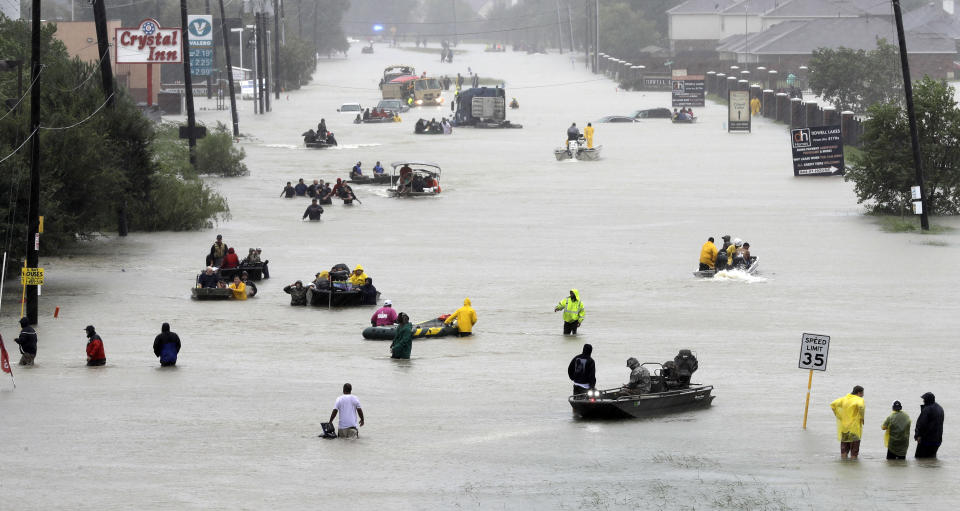 FILE - In this Aug. 28, 2017, file photo, rescue boats float on a flooded street as people are evacuated from rising floodwaters brought on by Tropical Storm Harvey in Houston. Scientists say climate change is faster, more extensive and worse than they thought a quarter century ago. They've concluded climate change has caused more rain in hurricanes Harvey, Maria, Katrina and others. (AP Photo/David J. Phillip, File)