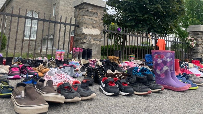 <p>Children's shoes were placed in front of a church in Kahnawake, in memory of the 215 children whose remains were found in a mass grave at a residential school in Kamloops, British Columbia. (Chloe Ranaldi/CBC)</p> 