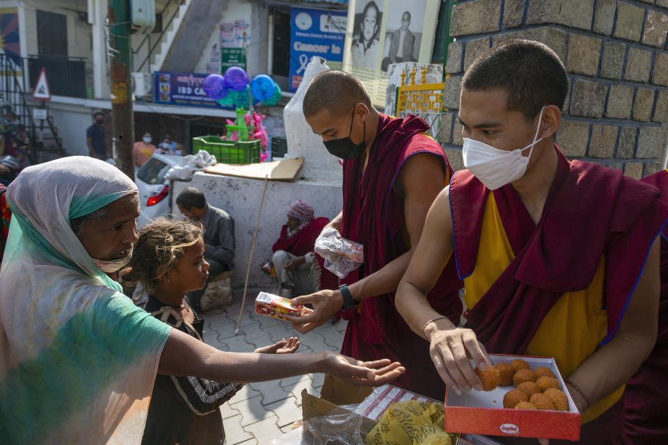 Exile Tibetan Buddhist monks distribute sweets and packets of juice to the public to celebrate the 86th birthday of their spiritual leader the Dalai Lama, outside the gate of their monastery in Dharmsala, India, Tuesday, July 6, 2021. (AP Photo/Ashwini Bhatia)