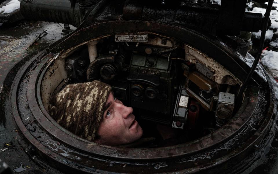 A Ukrainian serviceman pops his head up from inside a tank as he checks equipment near the Donetsk front line - YASUYOSHI CHIBA / AFP