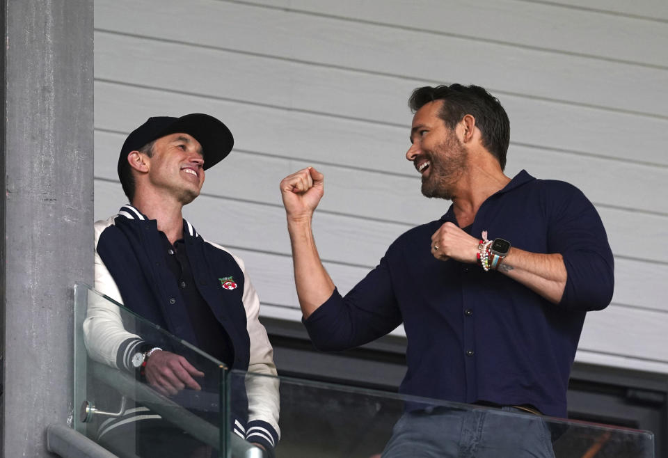 Wrexham co-owners Rob McElhenney, left, and Ryan Reynolds in the stands during the National League soccer match between Wrexham and Boreham Wood at The Racecourse Ground, in Wrexham, Wales, Saturday April 22, 2023. (Martin Rickett/PA via AP)