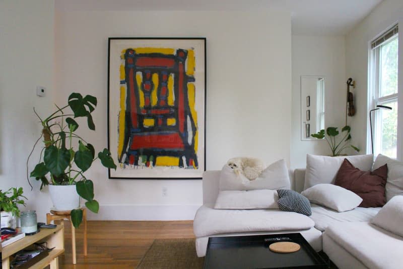 Art print on wall in plant filled living room.