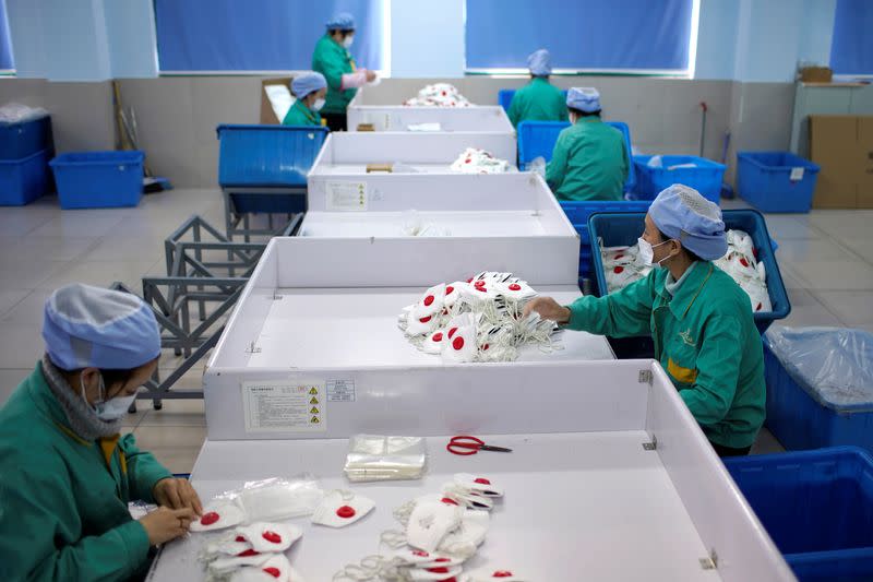 Workers are seen on a production line manufacturing masks at a factory in Shanghai