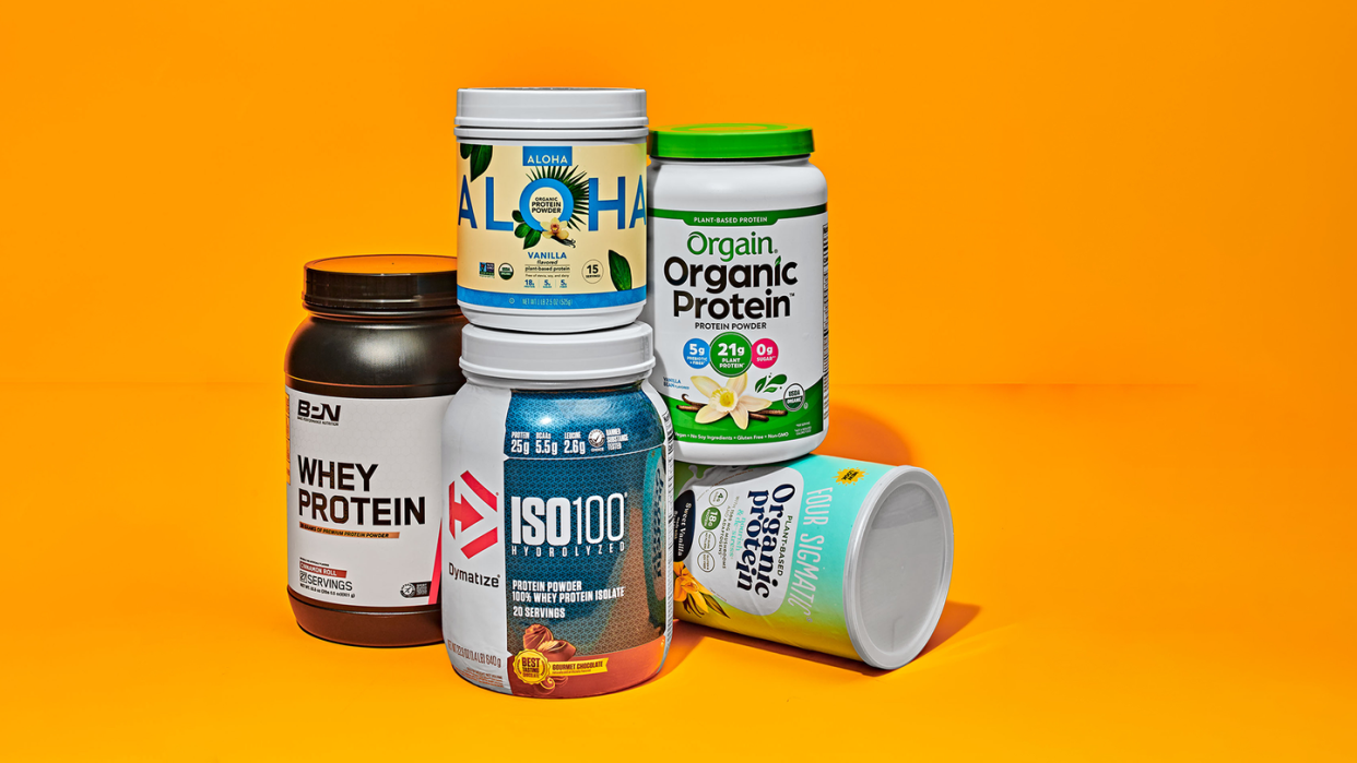 tubs of different brands of protein powder on orange background