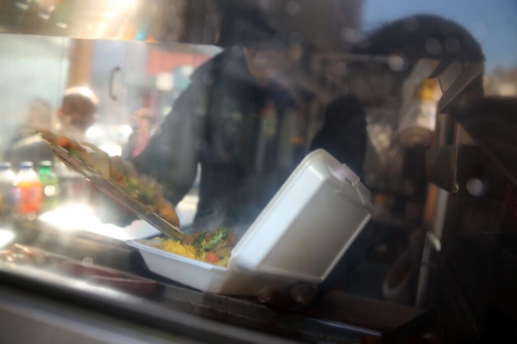 A restaurant worker loads up a Styrofoam container full of food