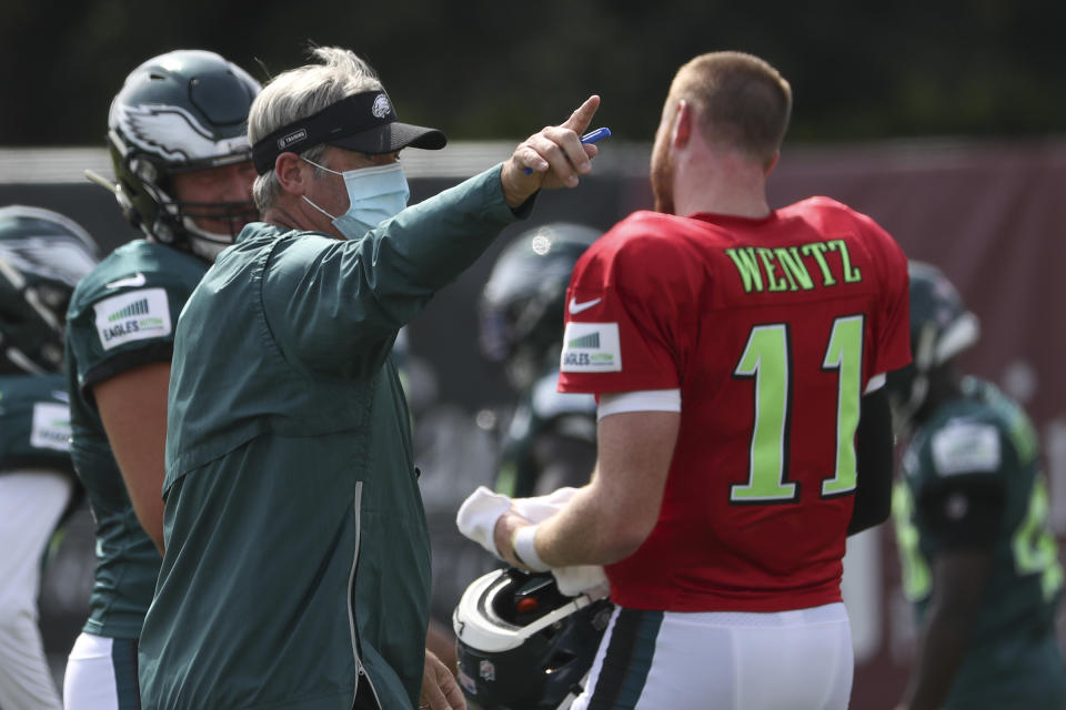 Philadelphia Eagles head coach Doug Pederson, left, gives instructions to quarterback Carson Wentz (11) during an NFL football training camp practice in Philadelphia, Friday, Aug. 21, 2020. (Heather Khalifa/Pool Photo via AP)