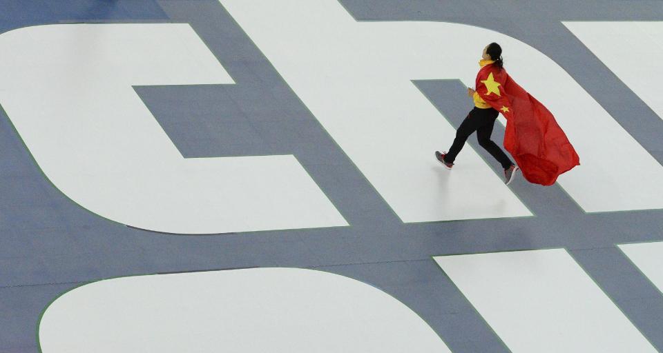 Gold medallist China's Zang Hong runs with her national flag for the flower ceremony after the women's 1,000-meter speedskating race at the Adler Arena Skating Center during the 2014 Winter Olympics in Sochi, Russia, Thursday, Feb. 13, 2014. (AP Photo/Antonin Thuillier, Pool)