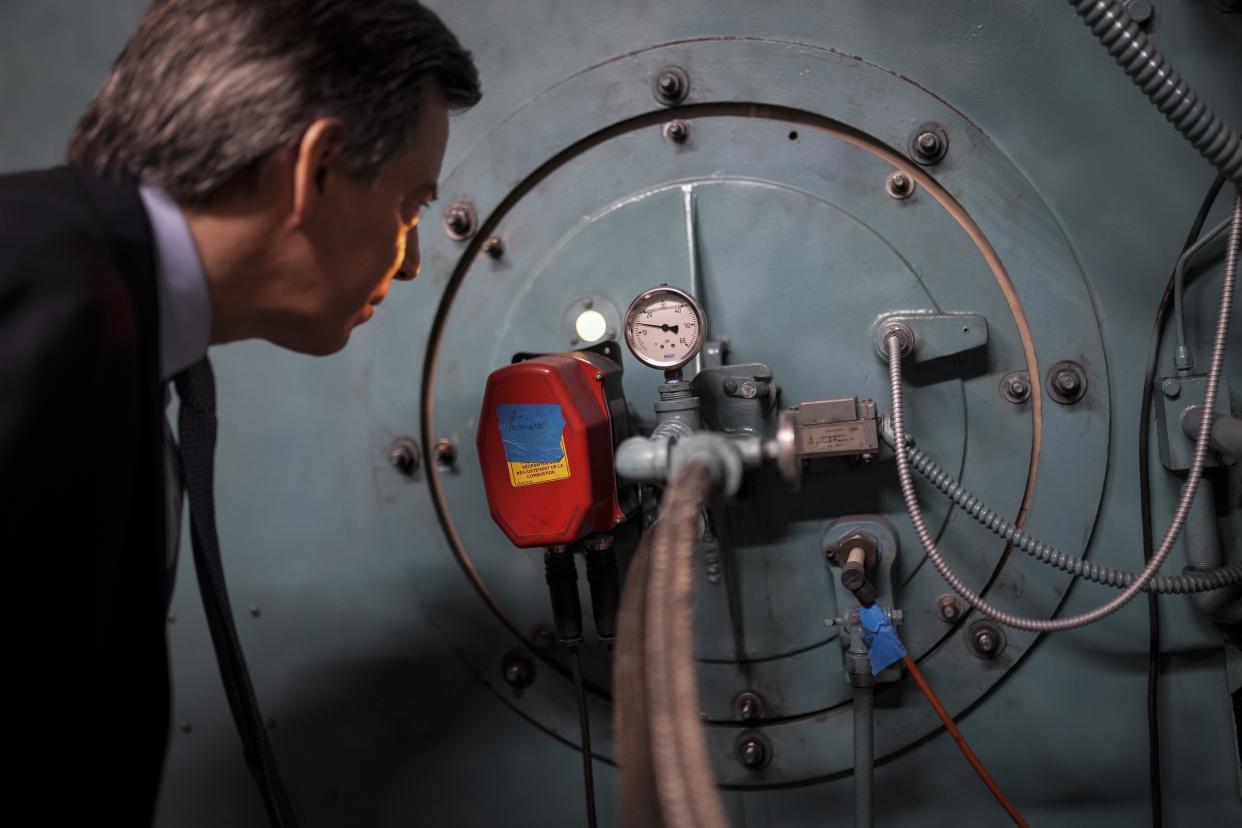 Josh London, senior vice president at Glenwood Management Corp., peers into the port hole of a natural gas fired boiler, located in the basement of The Grand Tier luxury apartment building, that his company uses to produce liquid carbon dioxide, Tuesday, April 18, 2023, in New York. New York is forcing buildings to clean up, and several are experimenting with capturing the carbon dioxide, cooling it into a liquid and mixing it into concrete where it turns into a mineral. (AP Photo/John Minchillo)