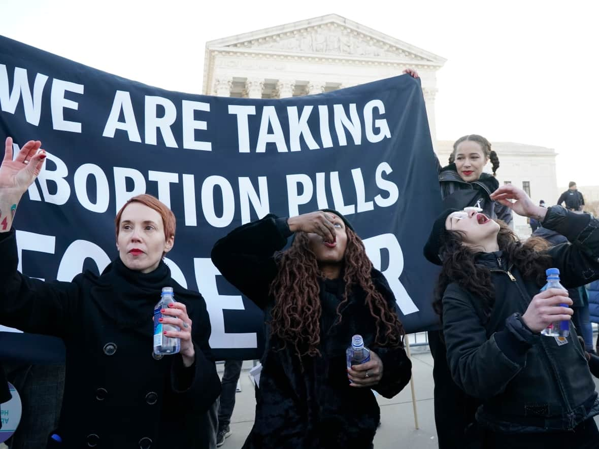 Women take abortion pills to make a statement about how safe and available they believe they are, as they demonstrate in front of the U.S. Supreme Court in Washington, D.C., on Dec. 1, 2021. The overturning of Roe v. Wade means the legal status of medication used to terminate pregnancy is set to enter a murkier legal zone. (Jacquelyn Martin/The Associated Press - image credit)