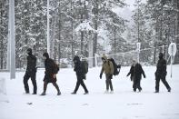 Finnish Border Guards escort migrants arriving at the Raja-Jooseppi international border crossing station between Russia and Finland, in Inari, northern Finland, Saturday, Nov. 25, 2023. The European Union’s border agency says that it will send dozens of officers and equipment as reinforcements to Finland to help police its borders amid suspicion that Russia is behind an influx of migrants arriving to the country. (Emmi Korhonen/Lehtikuva via AP)