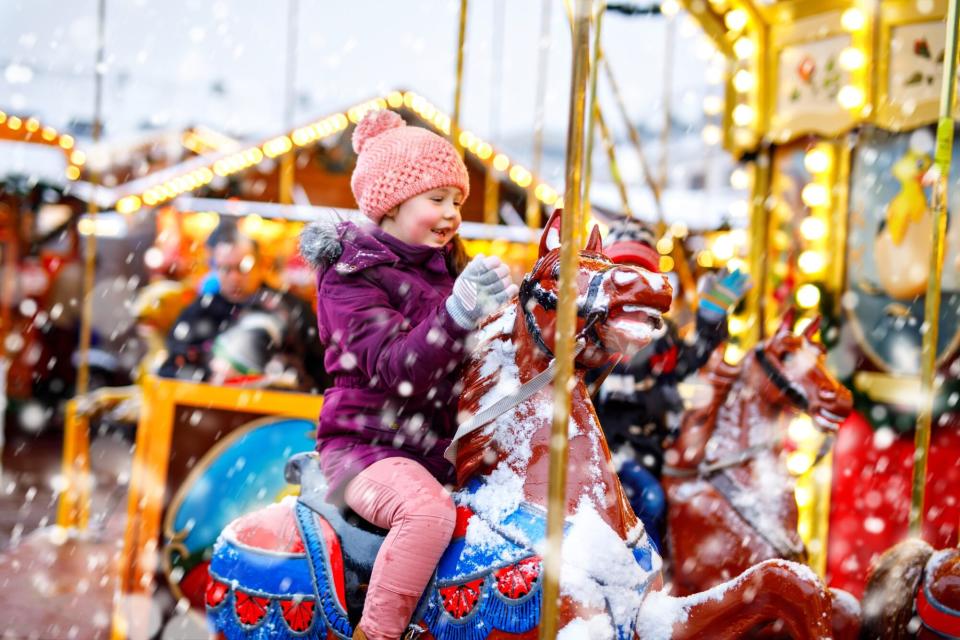 An image of little girl on a carousel in the snow.