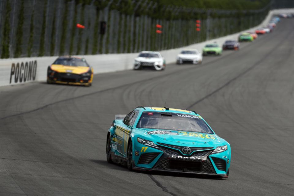 Denny Hamlin front, speeds down the track during the 2023 NASCAR Cup Series race at Pocono Raceway.