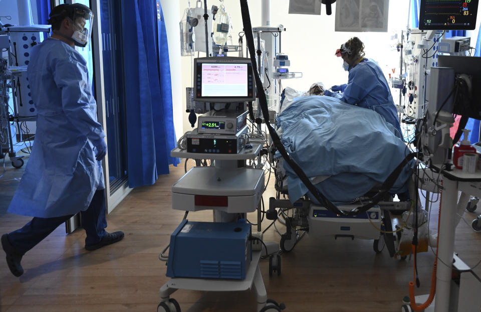 Members of the clinical staff wearing Personal Protective Equipment PPE care for a patient with coronavirus in the intensive care unit at the Royal Papworth Hospital in Cambridge, England, Tuesday May 5, 2020. (Neil Hall/Pool via AP)