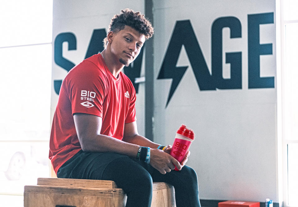 Patrick Mahomes wears a red BioSteel shirt and holds a red BioSteel cup.