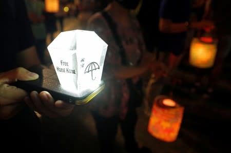 A person places a small mock up lantern on his mobile phone as people gather at Lennon Wall at Admiralty district during the Mid-Autumn Festival, in Hong Kong
